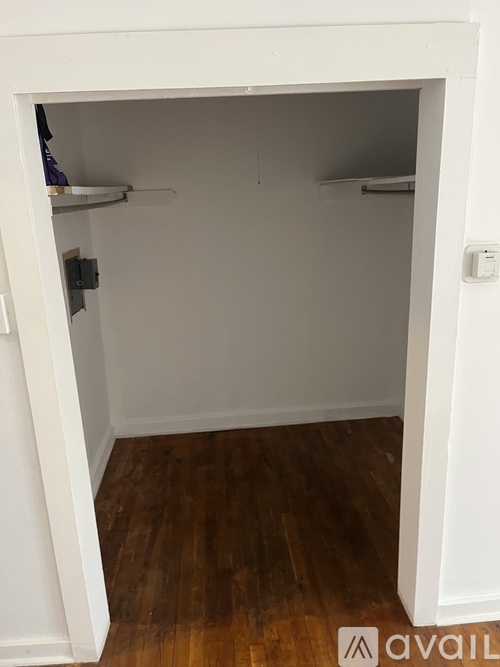 A small white closet with a wooden floor.