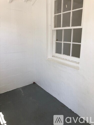 A window in a white room with a grey floor.