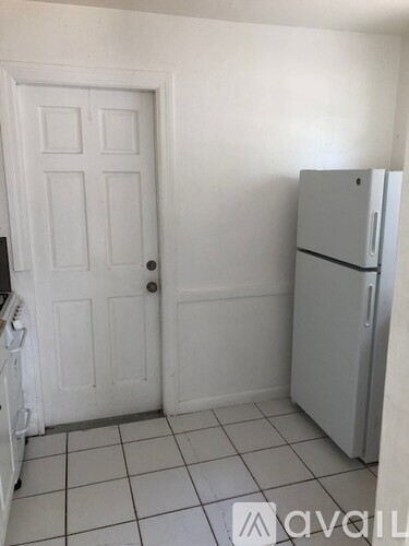 A white door is on the left and a white fridge is on the right.