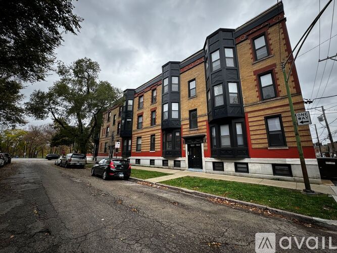 A row of multi-story apartment buildings with cars parked in front.