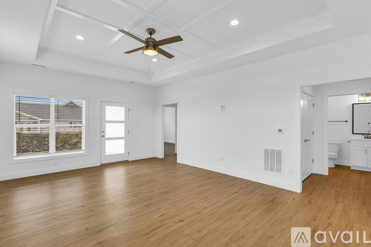 A spacious room with wooden floors and a ceiling fan.