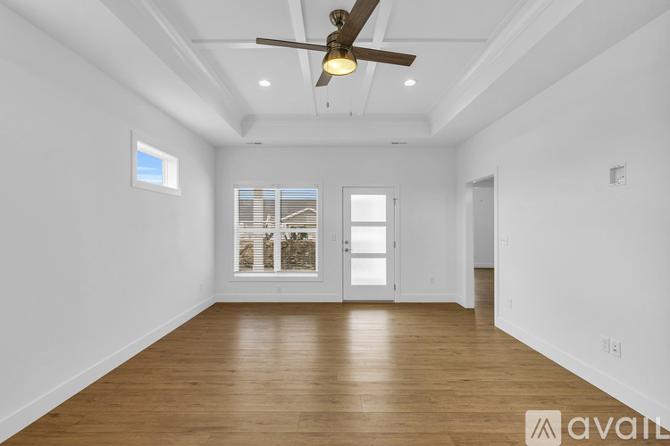 A spacious room with wooden floors and a ceiling fan.