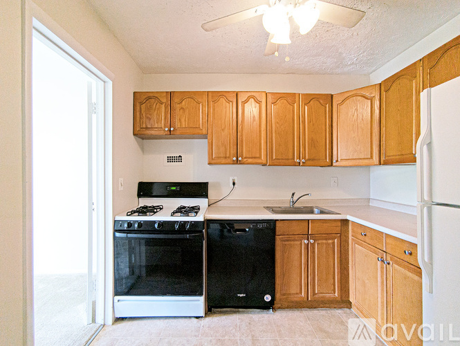 A kitchen with wooden cabinets and a black dishwasher.
