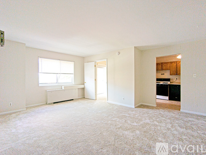 A spacious living room with a window and a door leading to another room.