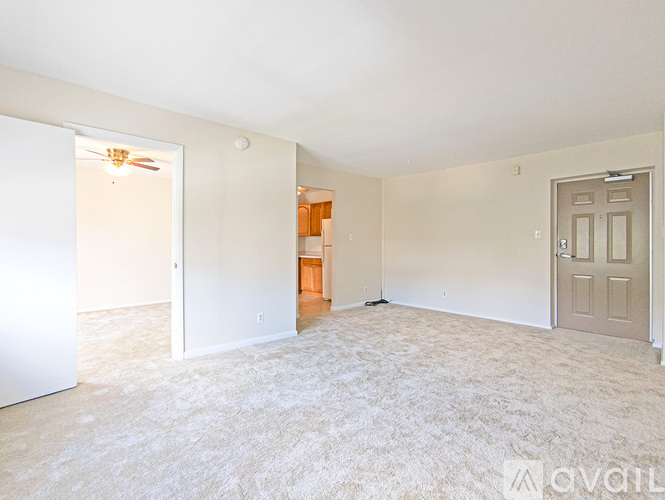 A spacious room with a carpeted floor and a ceiling fan.