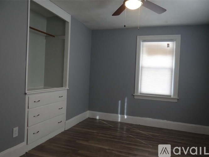 A room with a ceiling fan and a window with blinds.