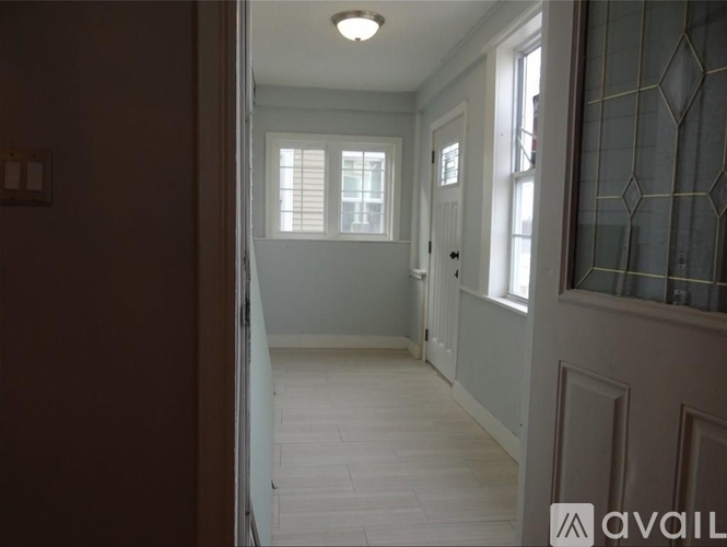 A hallway with a tiled floor and white walls.