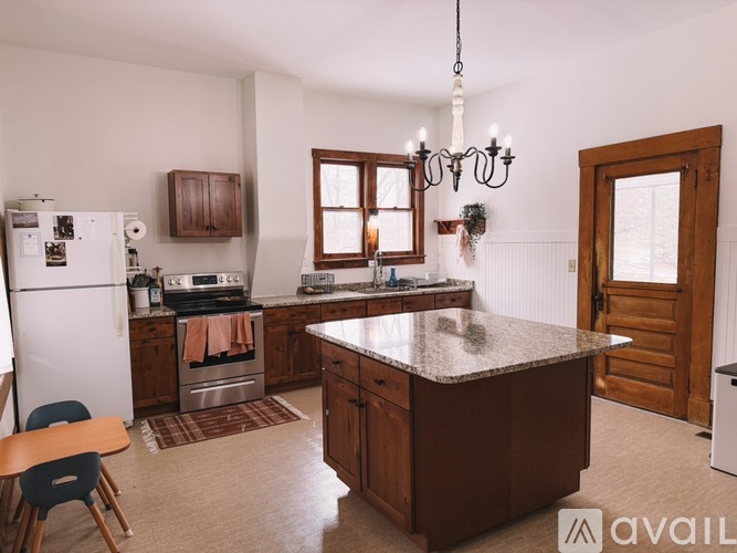A kitchen with a white refrigerator, wooden cabinets, and a granite countertop.
