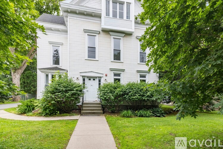 A white house with a grey front door and steps leading to it.