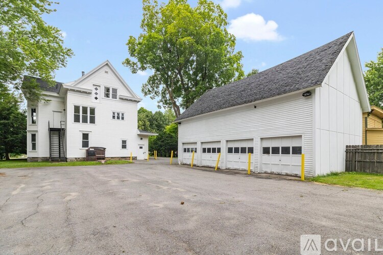 A large white building with a garage is surrounded by a parking lot.