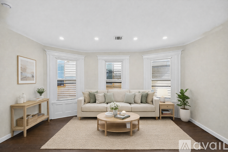 A living room with a white couch, a wooden coffee table, and a rug.