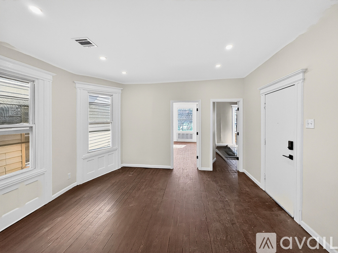 A spacious room with wooden flooring and white walls.