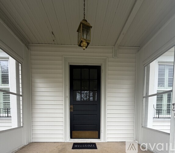 A black door with a glass panel and a welcome mat on a porch.