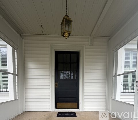 A black door with a glass panel and a welcome mat on a porch.