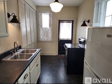 A kitchen with a sink, a refrigerator, and a window with blinds.