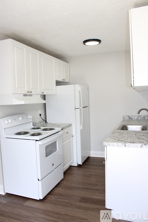 A white kitchen with a stove, refrigerator, and countertop.