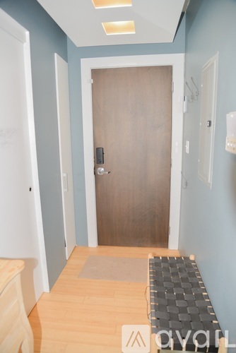A hallway with a wooden door and a black and white checkered mat on the floor.