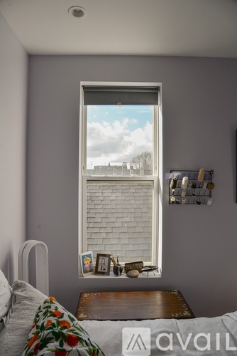 A bedroom with a bed, a window with a view of a cityscape, and a picture frame on the wall.