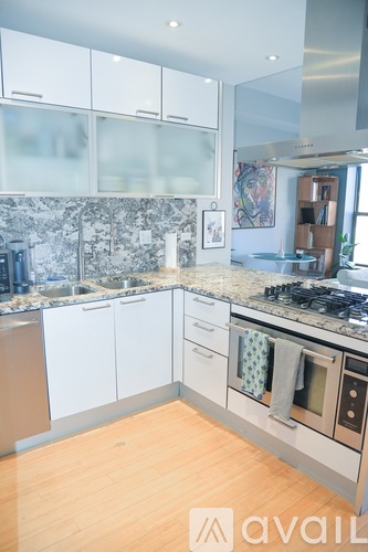 A kitchen with white cabinets and a wooden floor.
