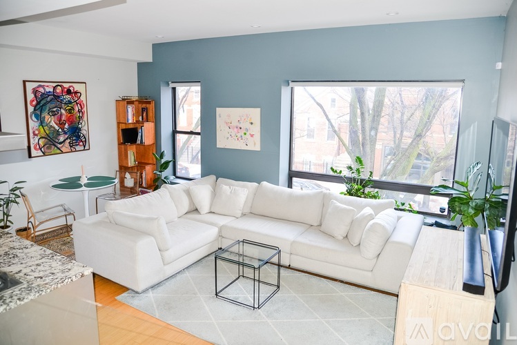 A living room with a white couch and a painting on the wall.
