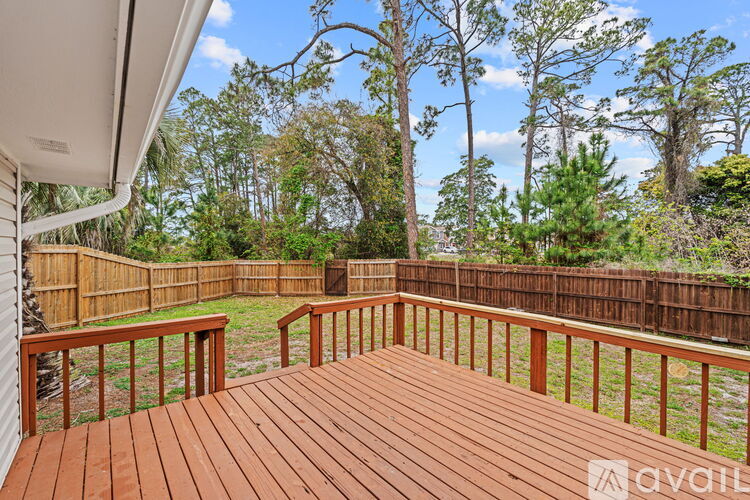 A wooden deck with a railing and trees in the background.