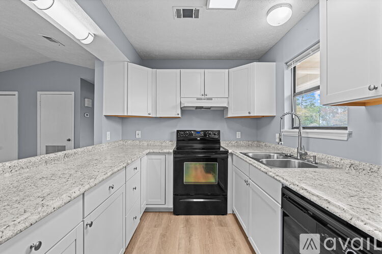 A kitchen with a black oven and white cabinets.