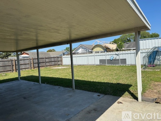 A covered patio area with a wooden floor and a white roof.