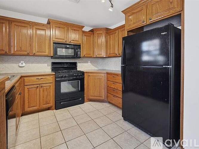 A kitchen with black appliances and wooden cabinets.