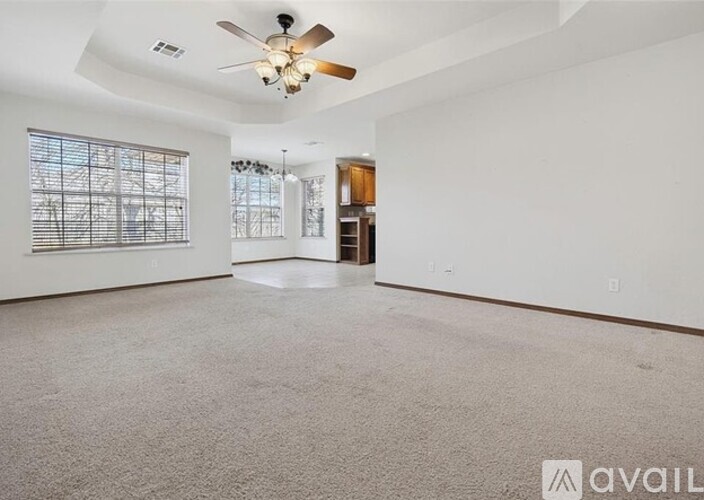 A spacious room with a ceiling fan and a large window.