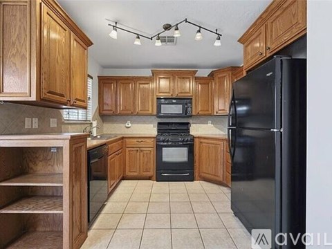 A kitchen with wooden cabinets and black appliances.