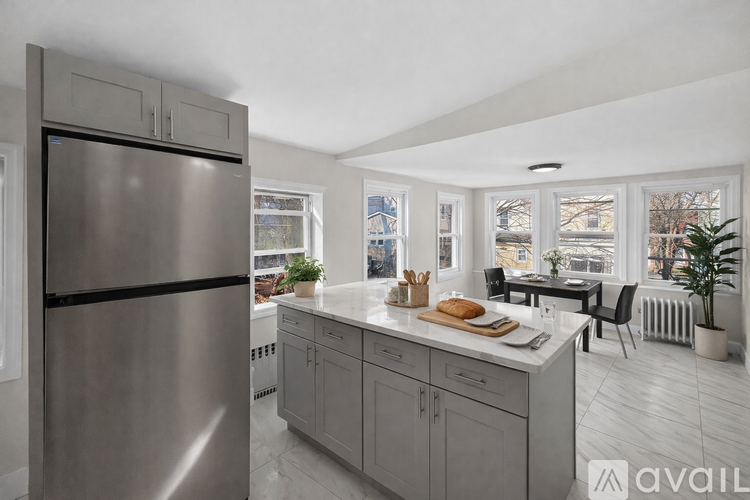 A modern kitchen with a stainless steel refrigerator and a marble countertop.