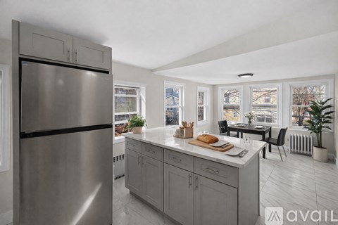 A modern kitchen with a stainless steel refrigerator and a marble countertop.