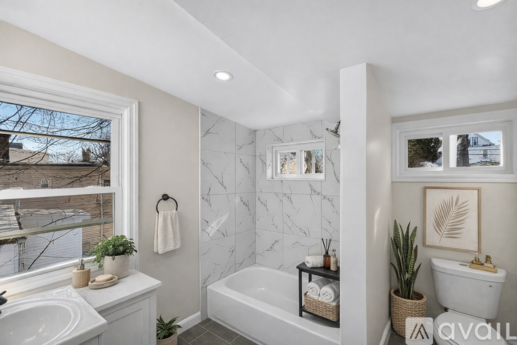 A bathroom with a marble patterned wall and a white bathtub.