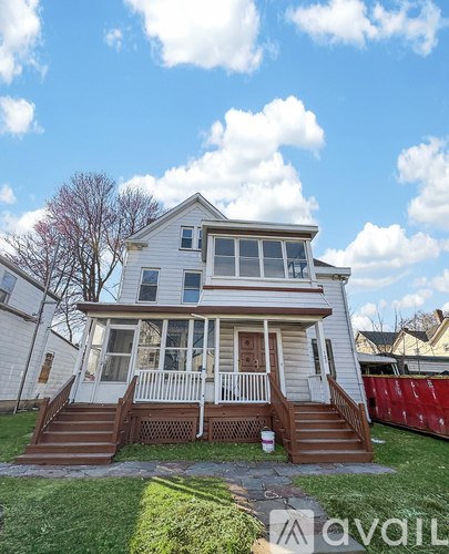 A two-story house with a white exterior and a brown deck.
