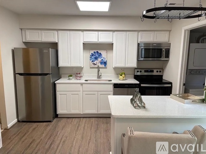 A kitchen with white cabinets and a stainless steel refrigerator.