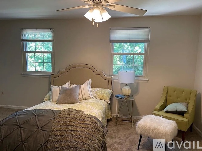 A bedroom with a bed, chair, and window.