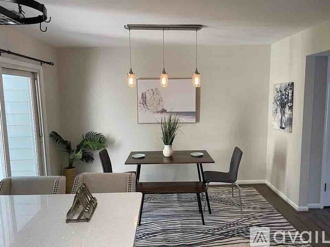 A dining room with a table, chairs, and a painting on the wall.