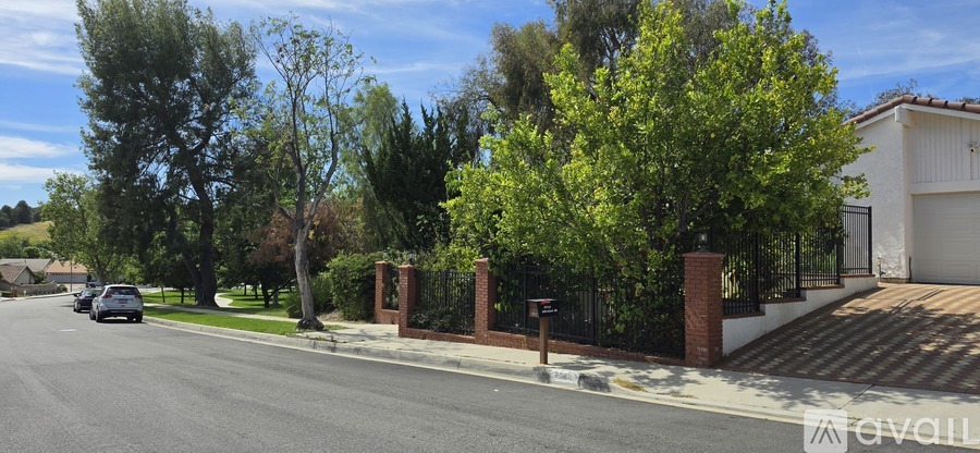 A street view with a house, trees, and a car.