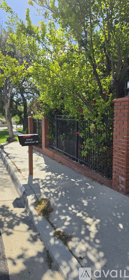 A black mailbox is on a wooden post on a sidewalk.