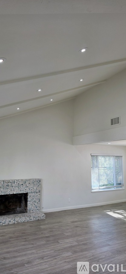 A spacious room with a fireplace and a window.