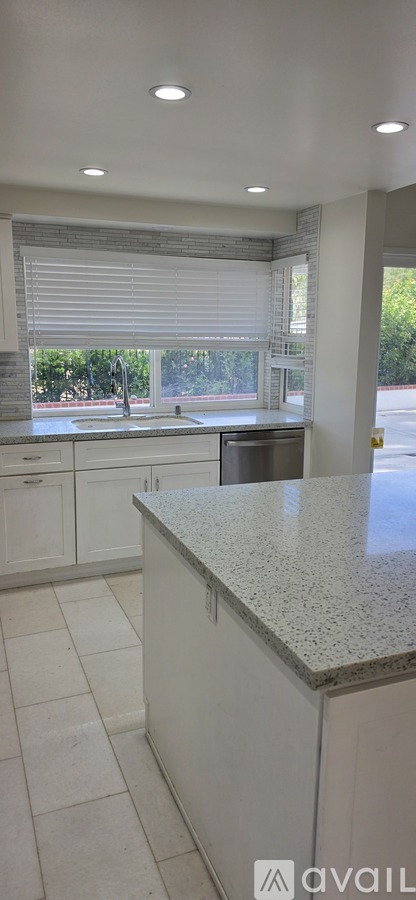 A kitchen with white cabinets and a granite countertop.