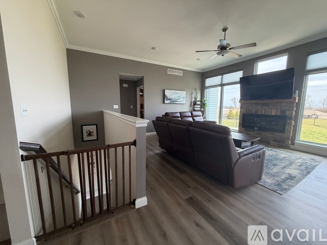 A living room with a brown couch and a ceiling fan.