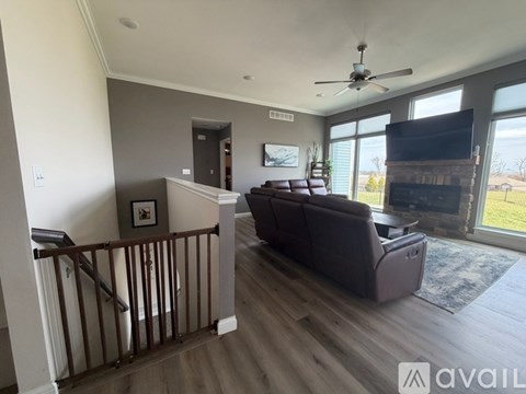 A living room with a brown couch and a ceiling fan.