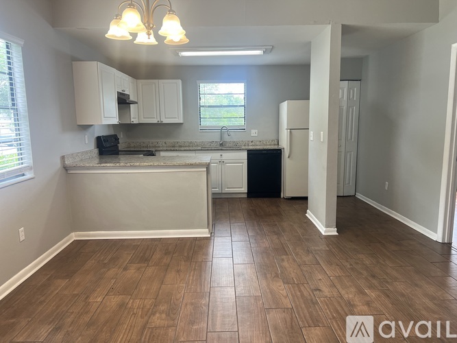 A kitchen with wood flooring and white cabinets.