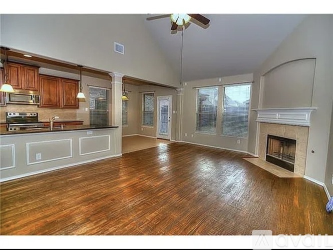 A spacious living room with wood flooring and a fireplace.