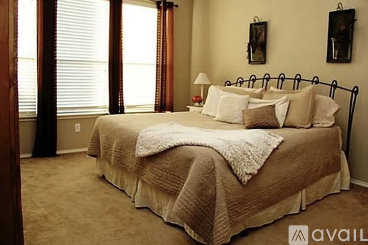 A bedroom with a large bed and a window with curtains.