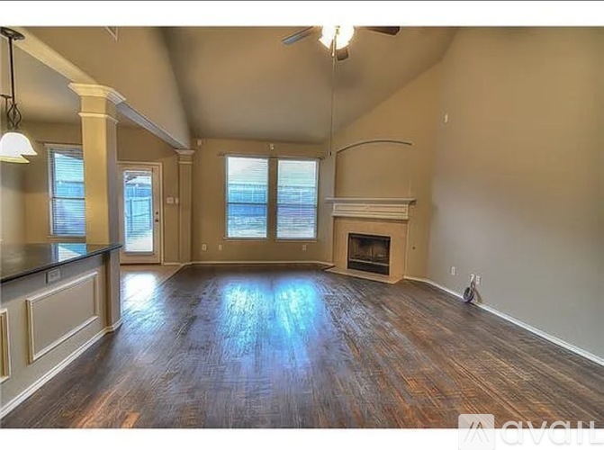 A spacious living room with wood flooring and a fireplace.