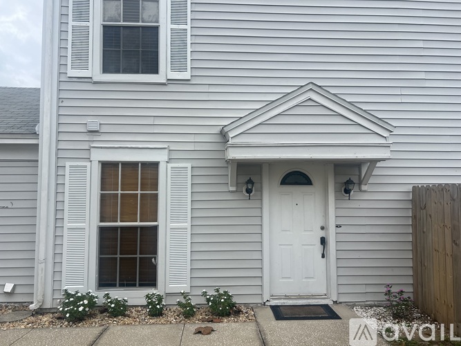 A white house with a grey siding and a white door.