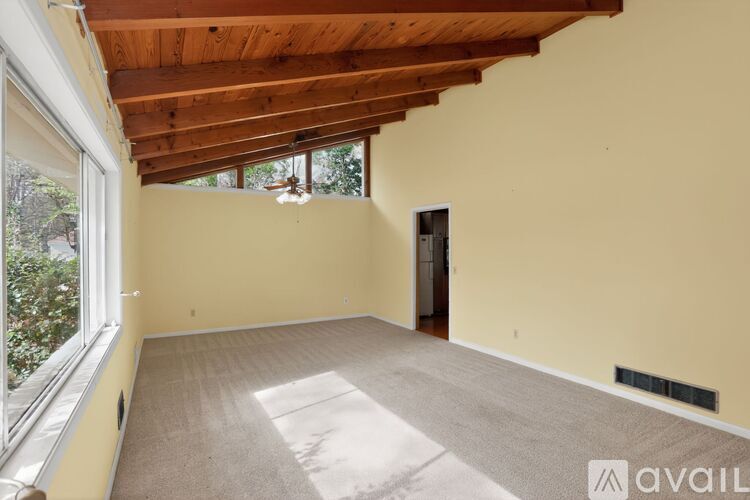 A spacious room with a wooden ceiling and a carpeted floor.