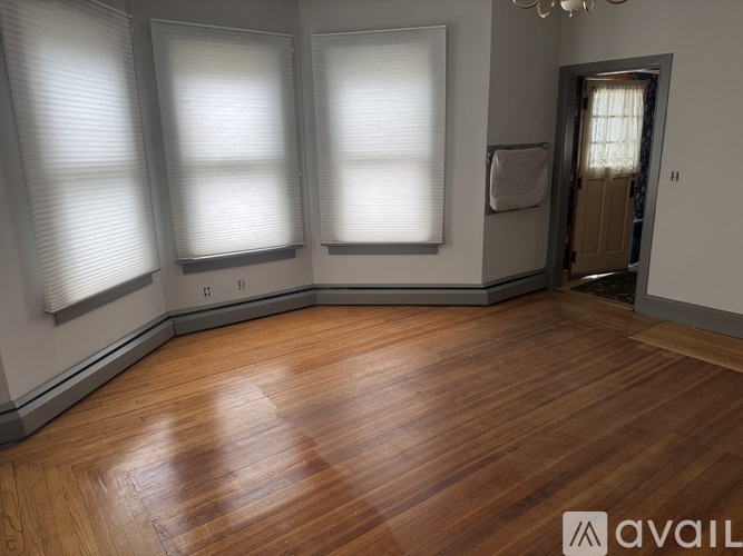 A room with wooden floors and three windows.